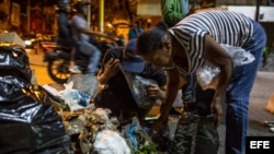 Varias personas buscan comida entre bolsas de basura, en Caracas. (Archivo)