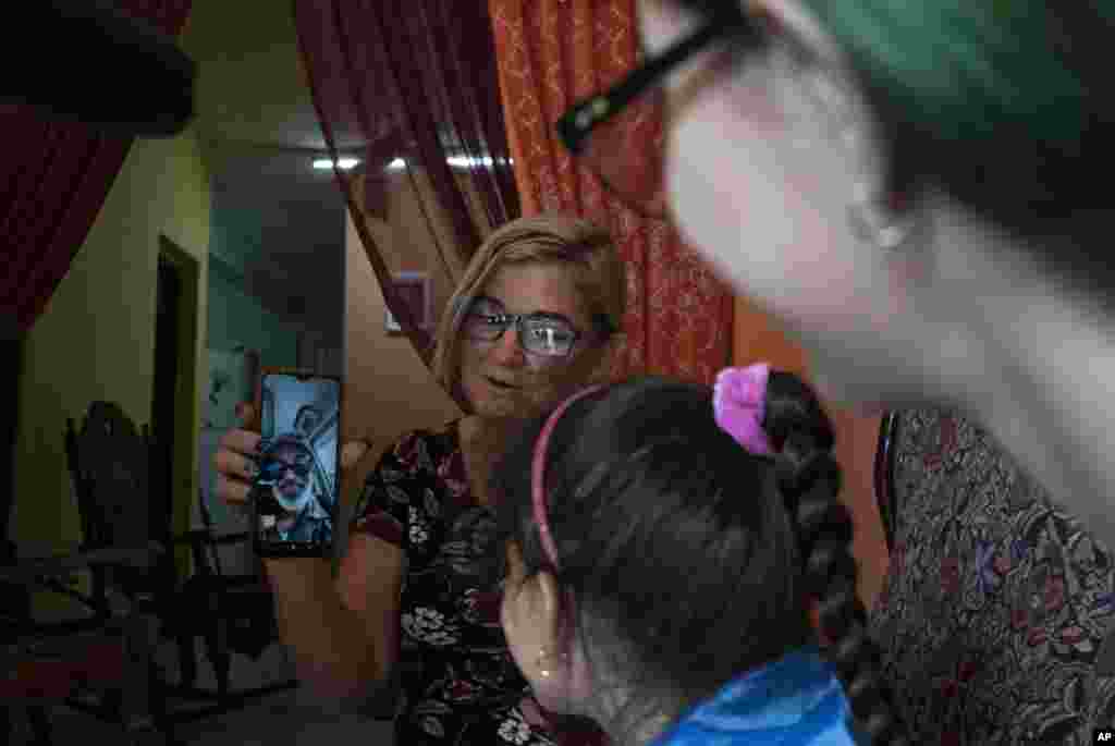 Danmara Triana sostiene su celular durante una videollamada con su esposo Roberto de la Iglesia, quien vive en Estados Unidos desde 2015 con su hijo. (AP Foto/Ramón Espinosa)